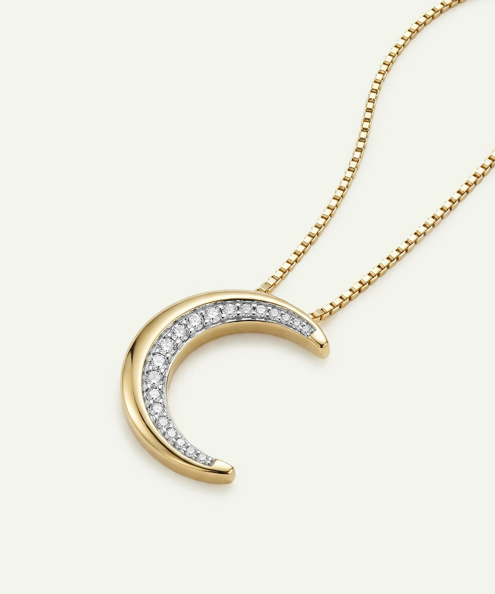 Gold crescent moon necklace with diamond accents on a white background