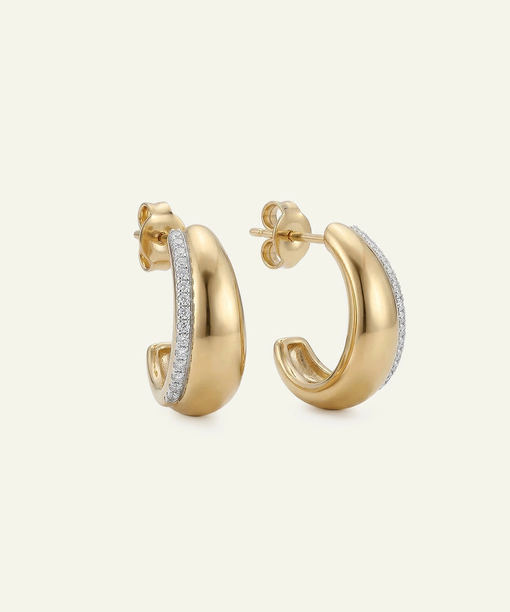 Gold hoop earrings with embedded diamonds on a light beige background
