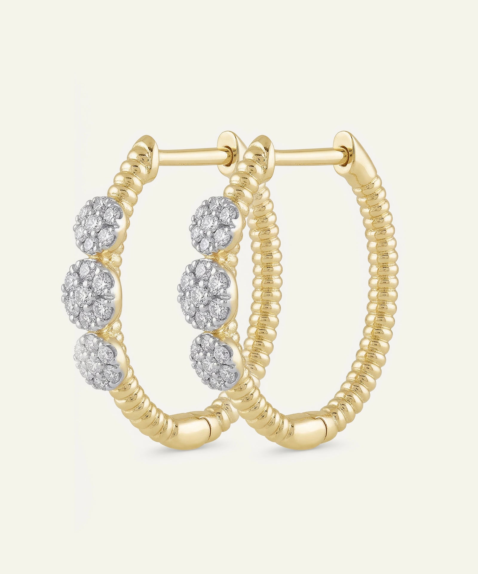 Gold hoop earrings with diamond accents on a light beige background