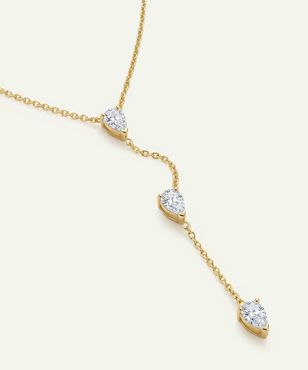 Gold necklace with diamond pendants on a light beige background
