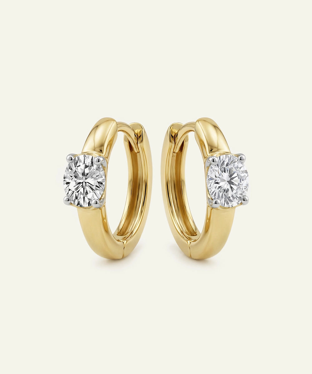 Gold hoop earrings with diamond accents on a light beige background