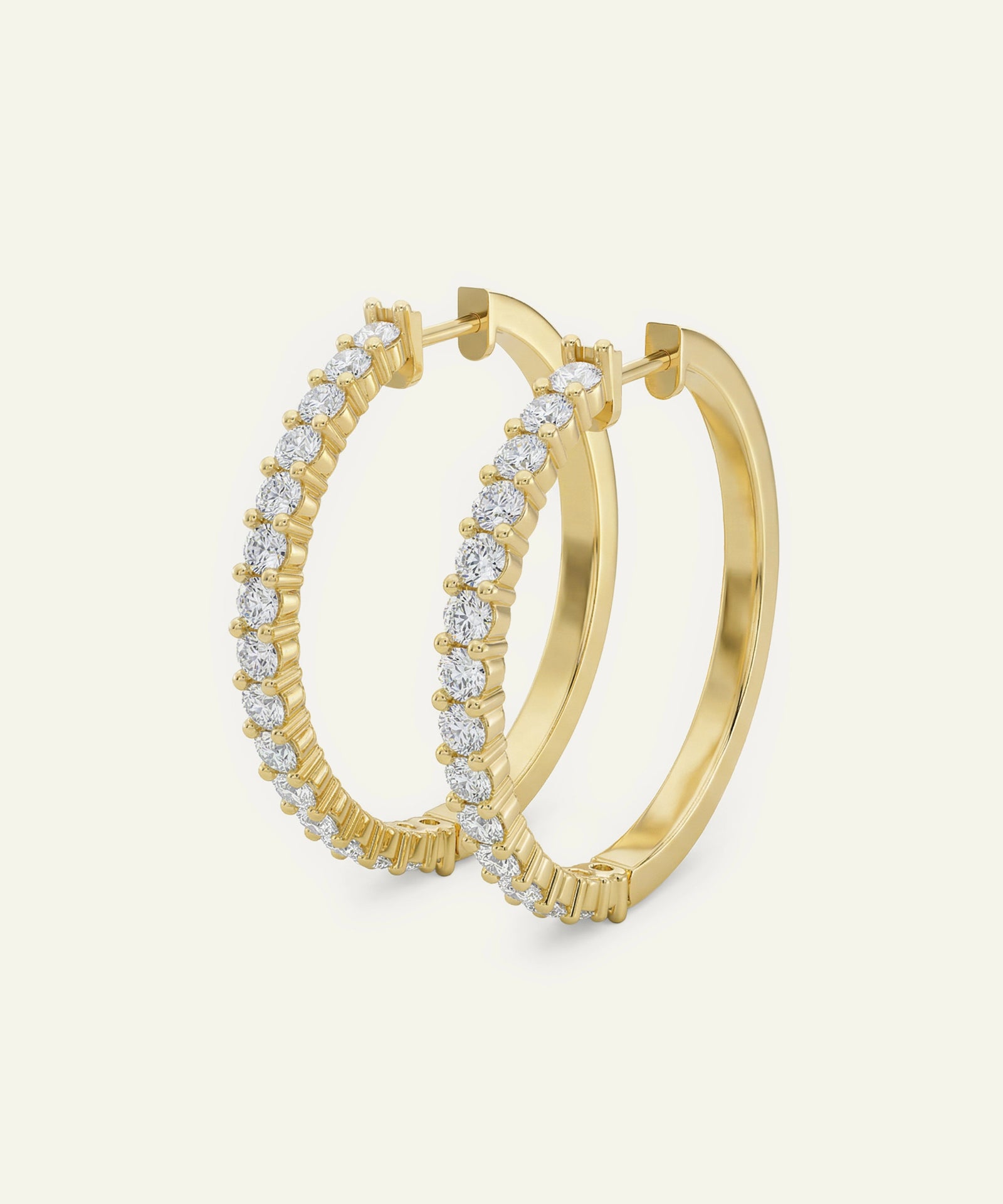 Gold hoop earrings with diamond accents on a light beige background