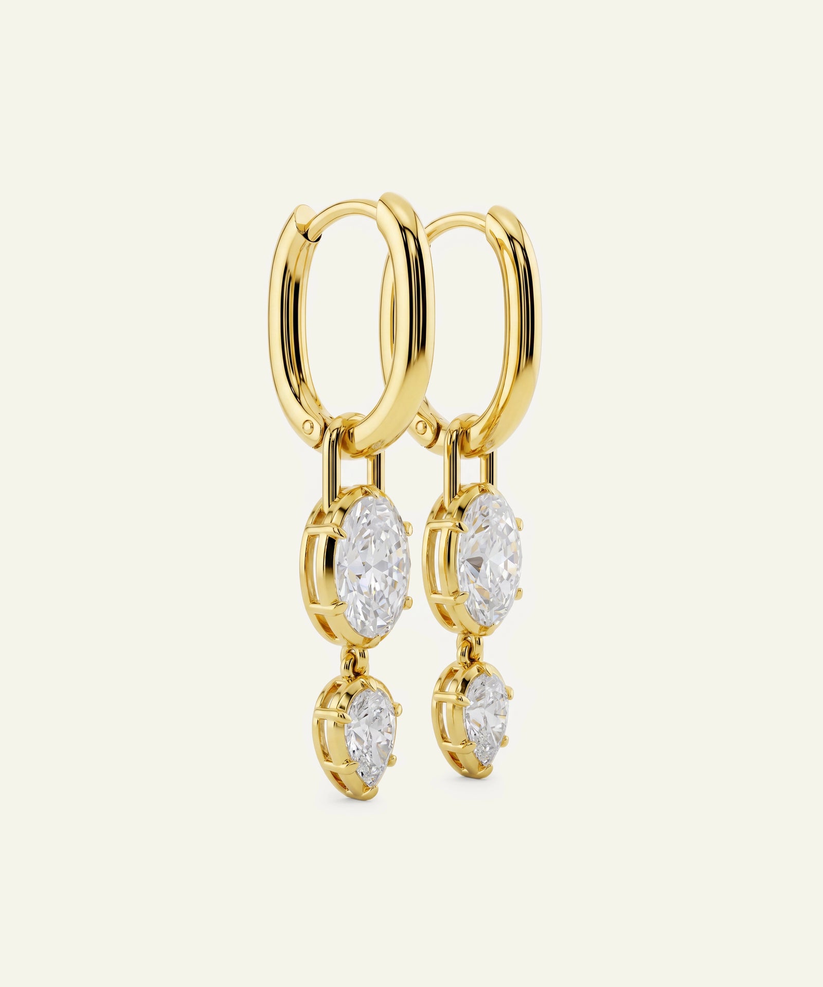 Gold hoop earrings with diamond drops on a beige background