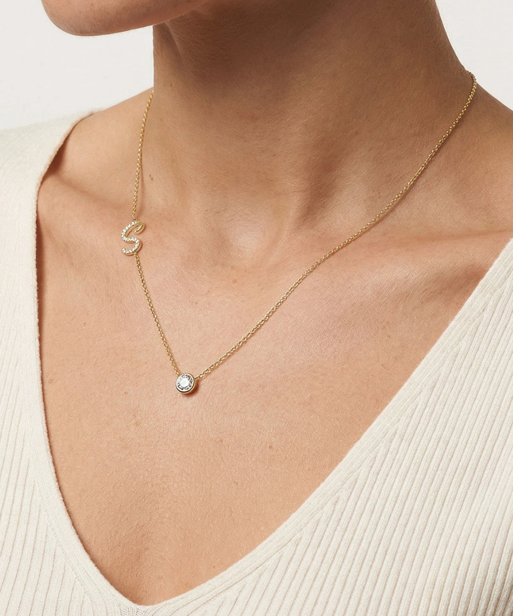 Gold necklace with a small pendant worn by a person in a white top