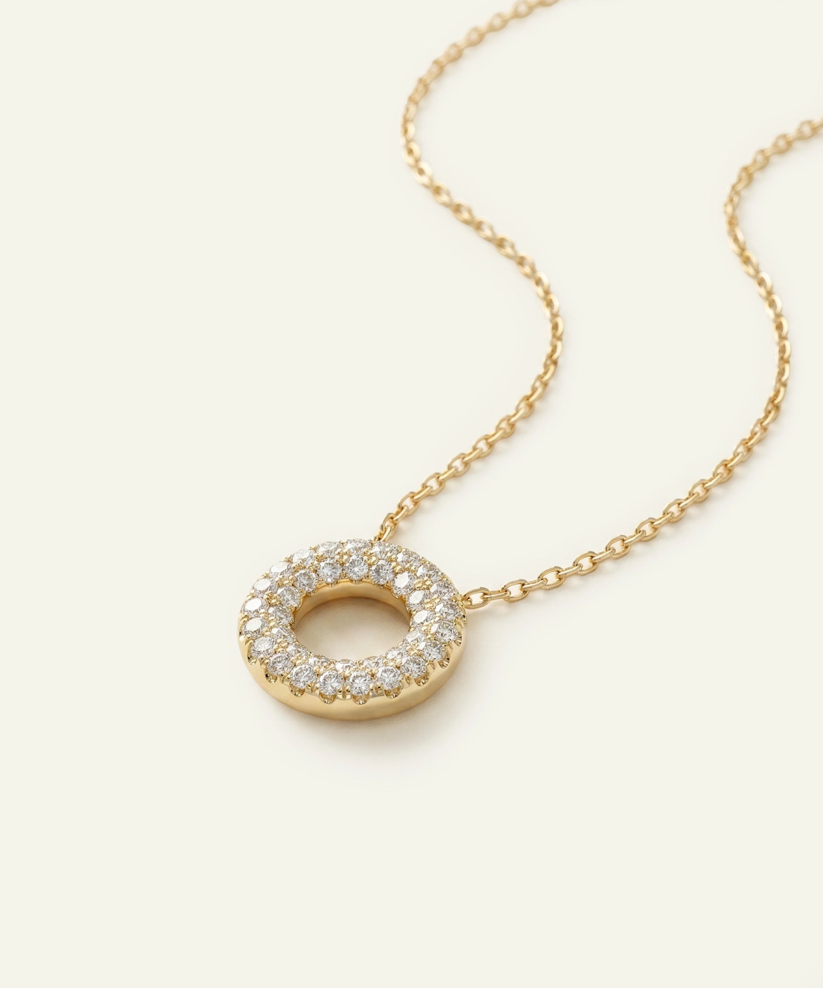 Gold necklace with a circular pendant on a white background