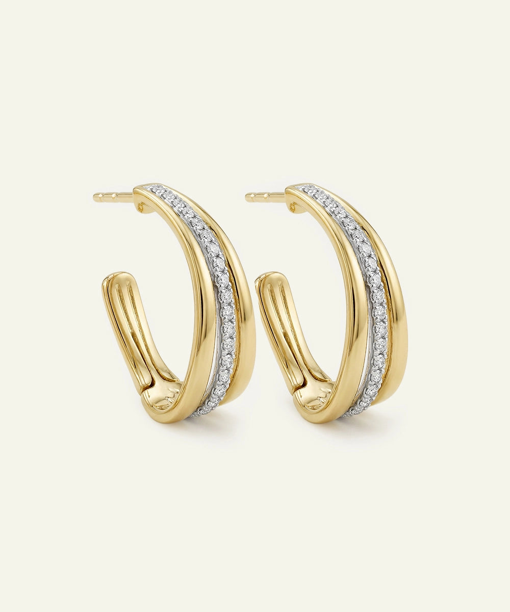 Gold hoop earrings with embedded diamonds on a light beige background