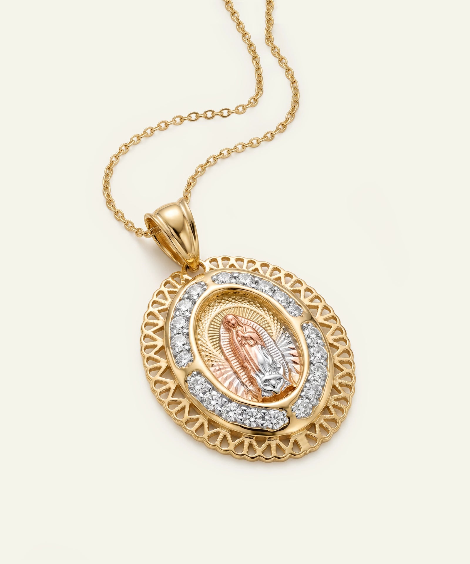Gold and rose gold pendant with intricate design on a beige background