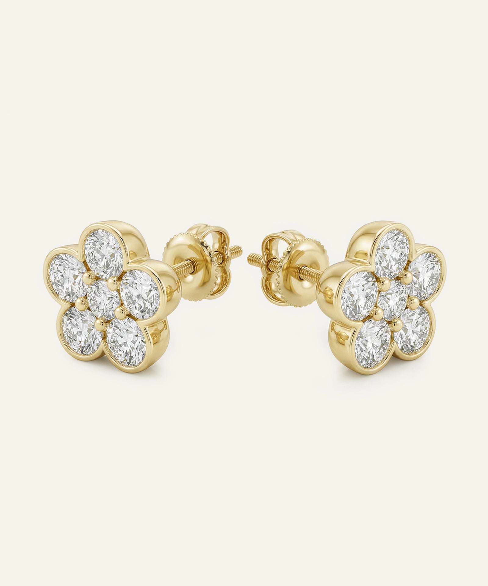 Gold earrings with diamond accents on a light beige background
