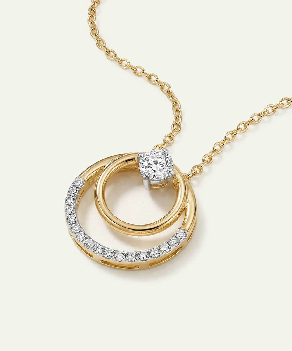 Gold necklace with interlocking rings and a central diamond on a light background