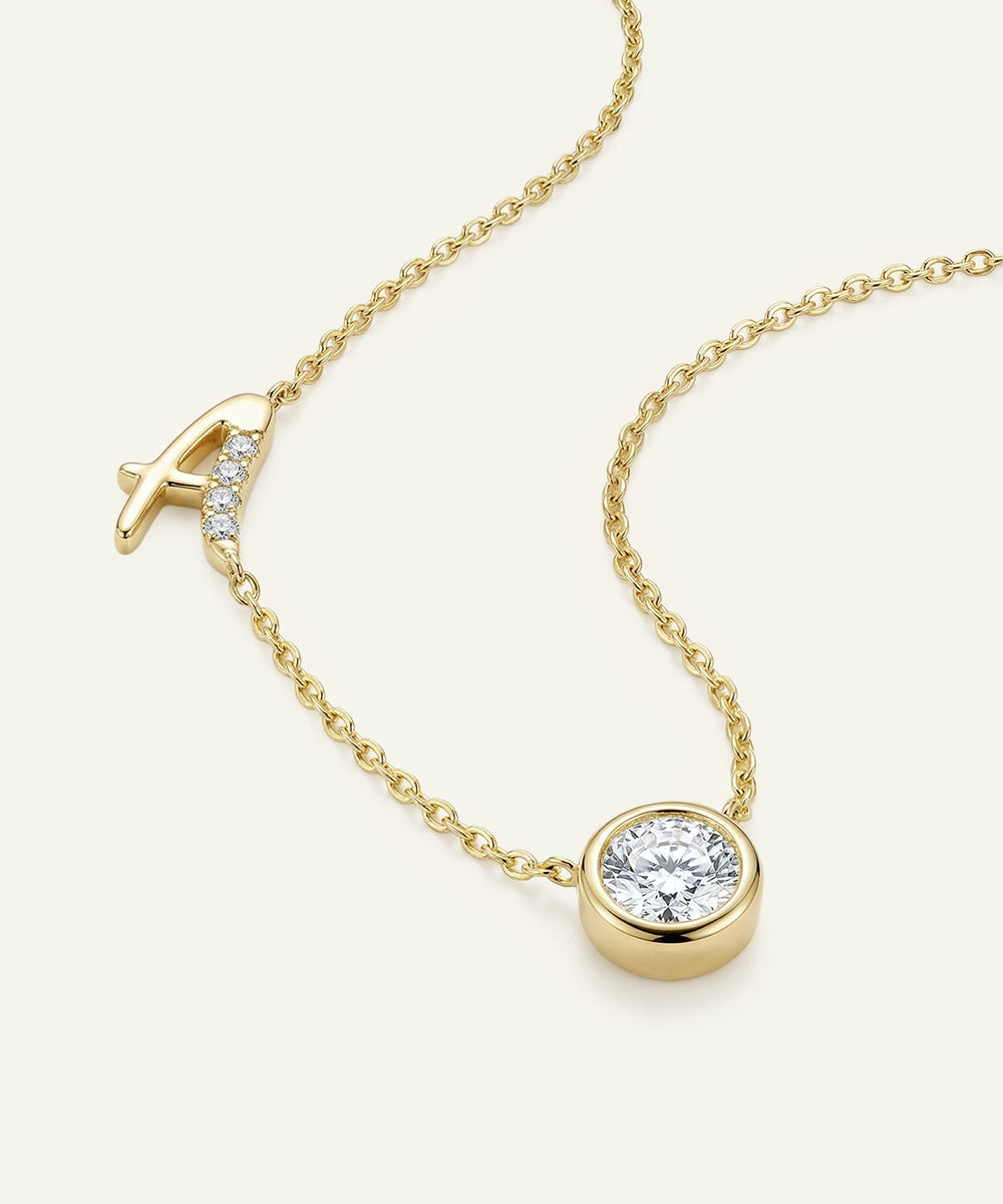 Gold necklace with a round diamond pendant on a white background