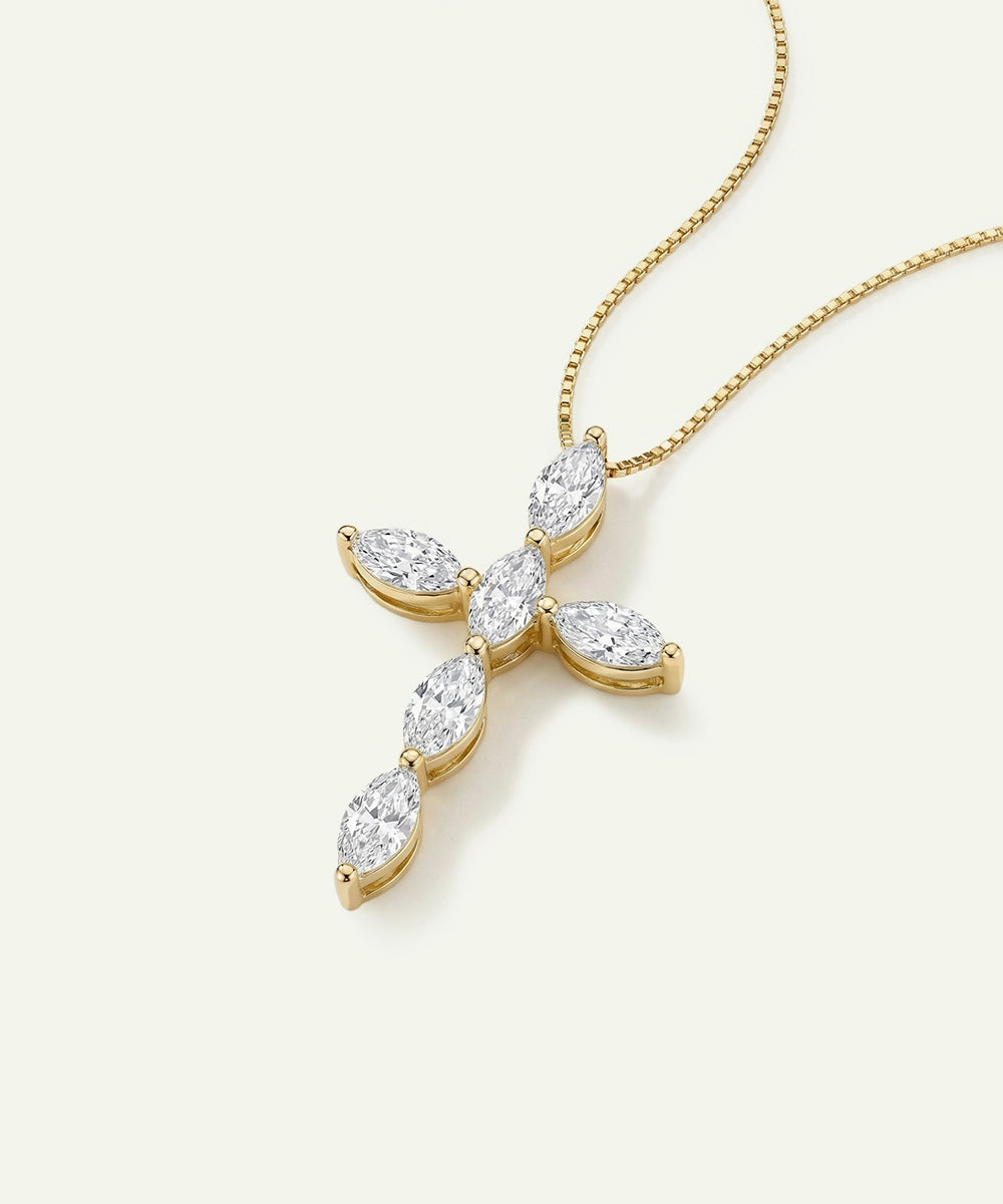 Gold cross-shaped necklace with diamond-like stones on a white background