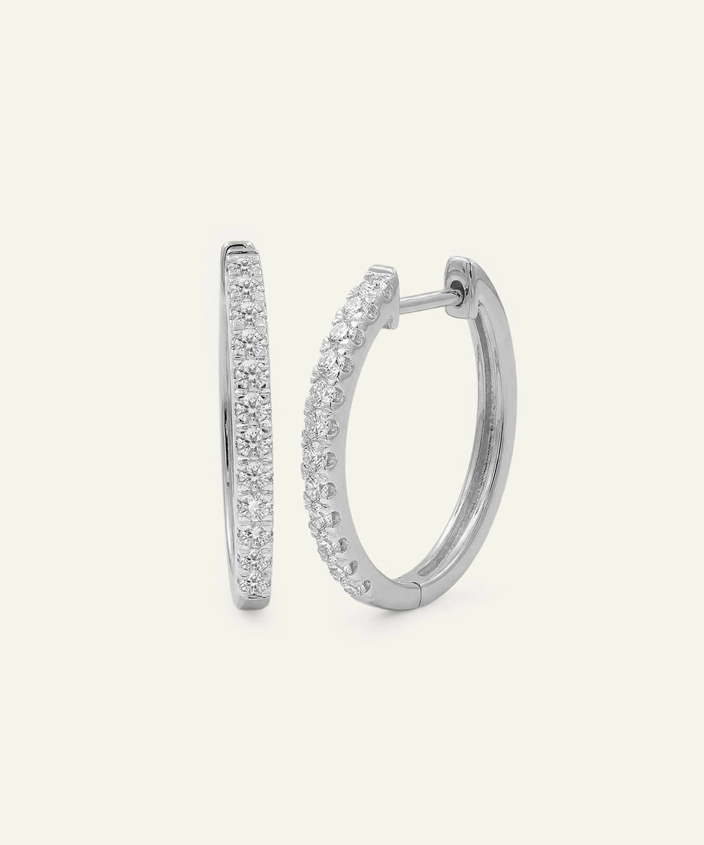 Silver hoop earrings with clear gemstones on a light gray background