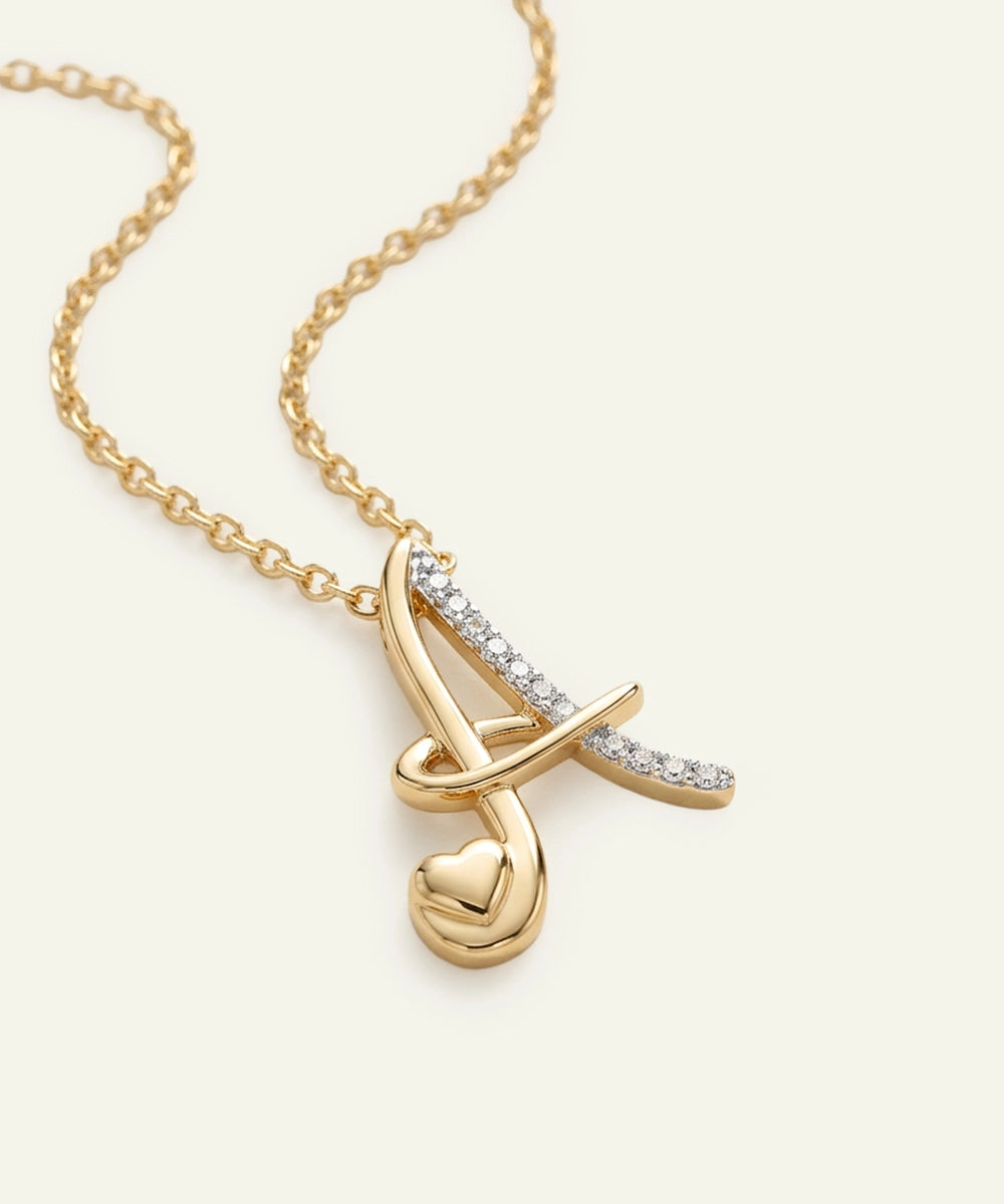 Gold necklace with a heart and bow design on a light beige background