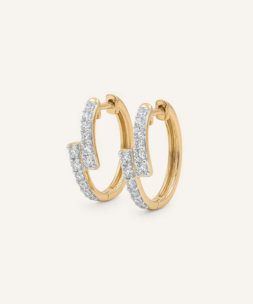 Gold hoop earrings with diamond accents on a light gray background