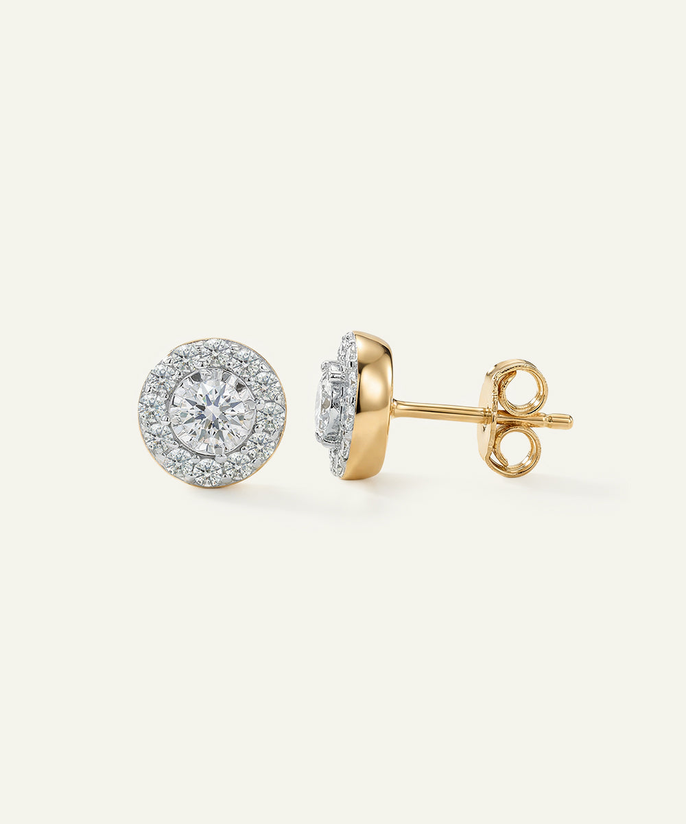 Pair of diamond stud earrings in gold and silver on a light beige background