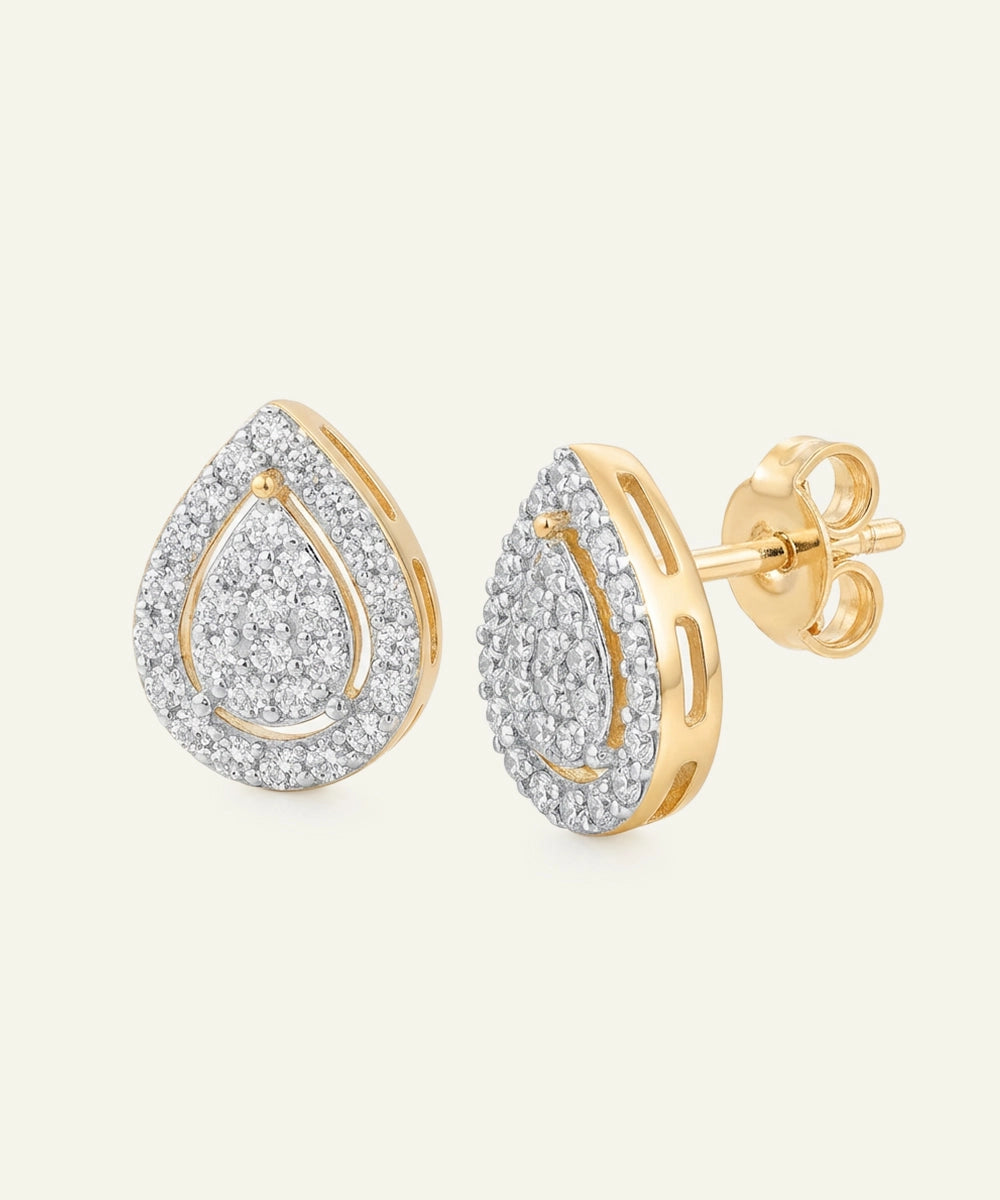 Gold and diamond teardrop earrings on a light beige background