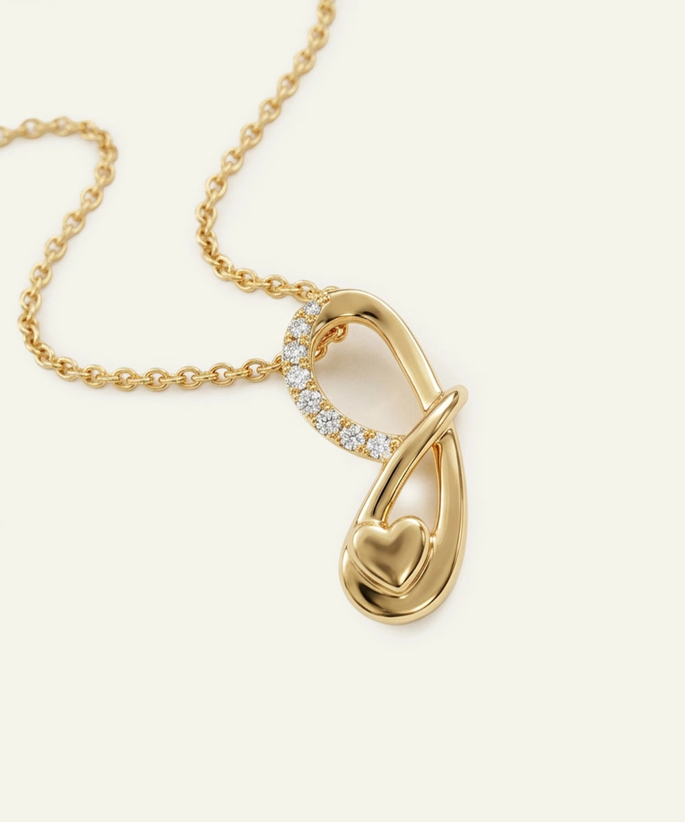 Gold necklace with a heart-shaped pendant on a light beige background