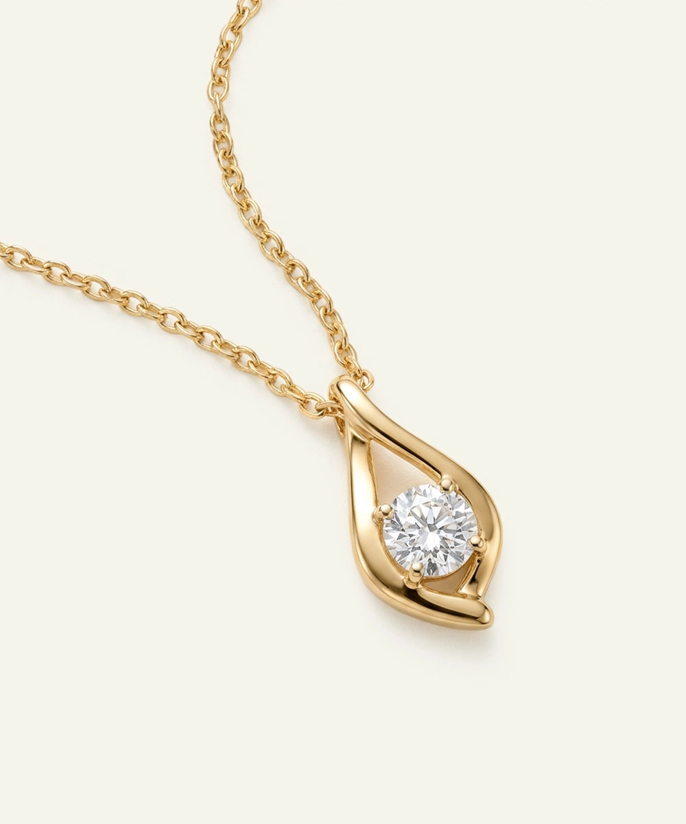 Gold necklace with a diamond pendant on a light beige background