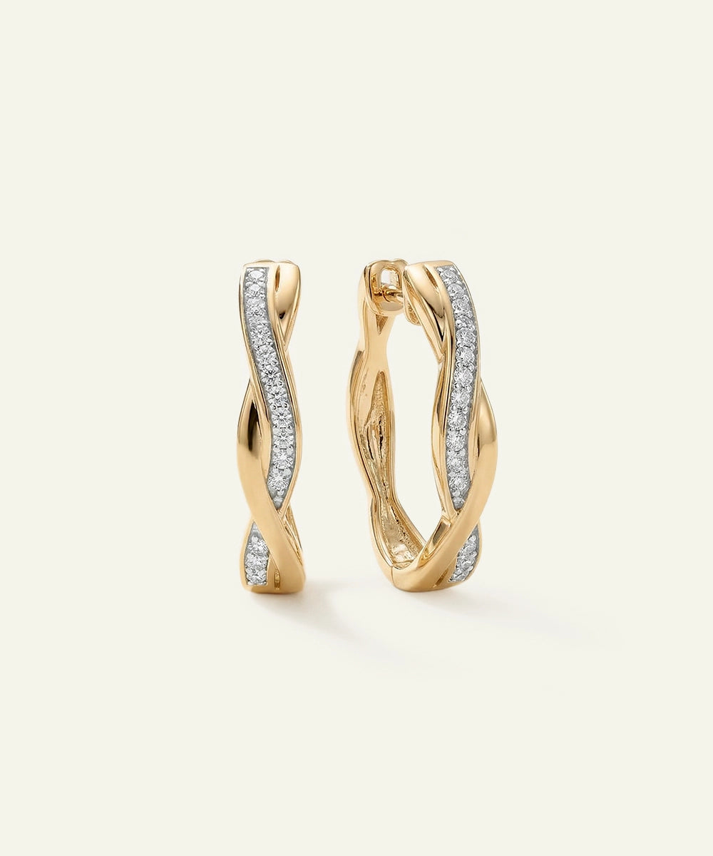 Gold hoop earrings with diamond accents on a light beige background