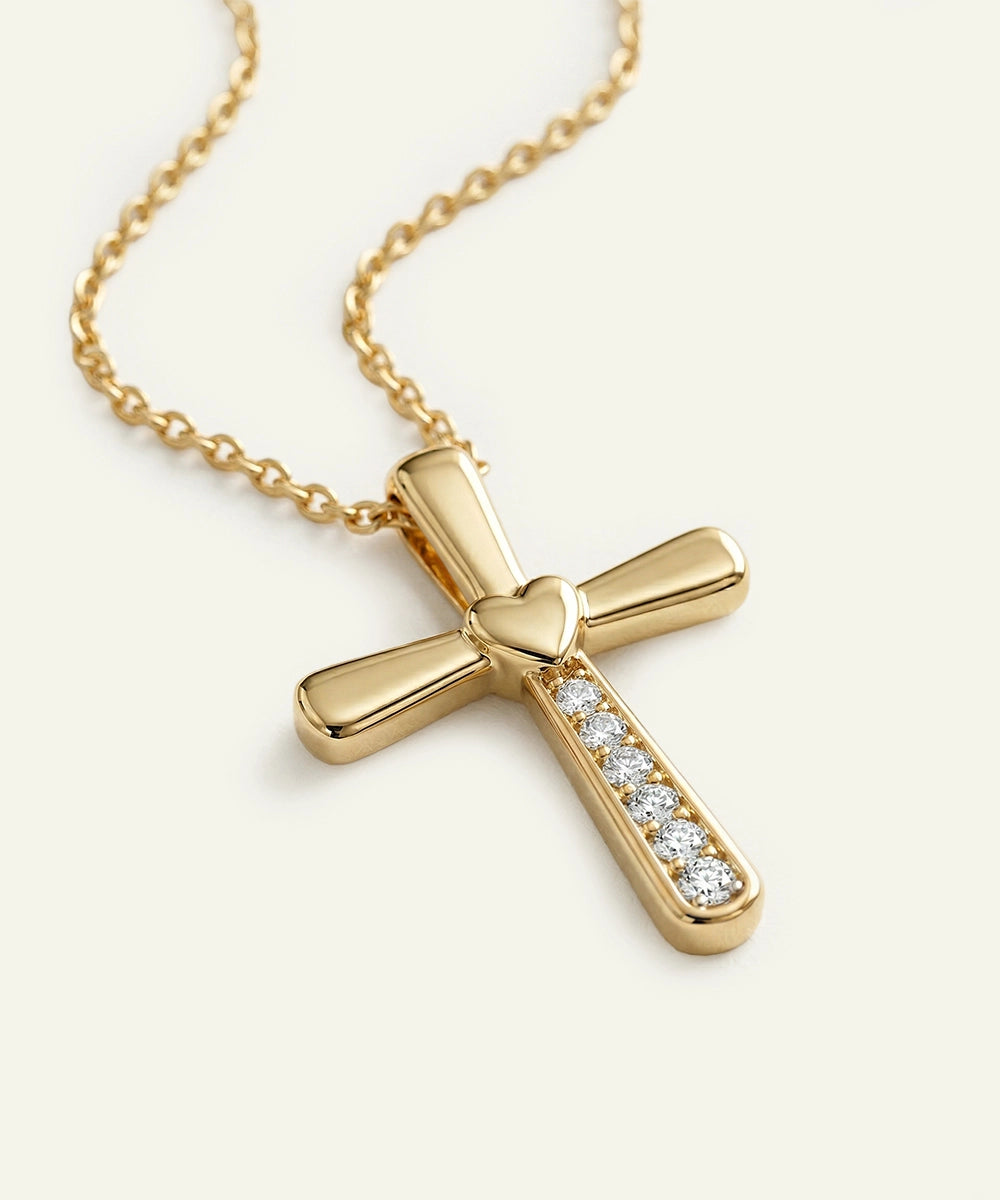 Gold cross necklace with diamond accents on a light beige background