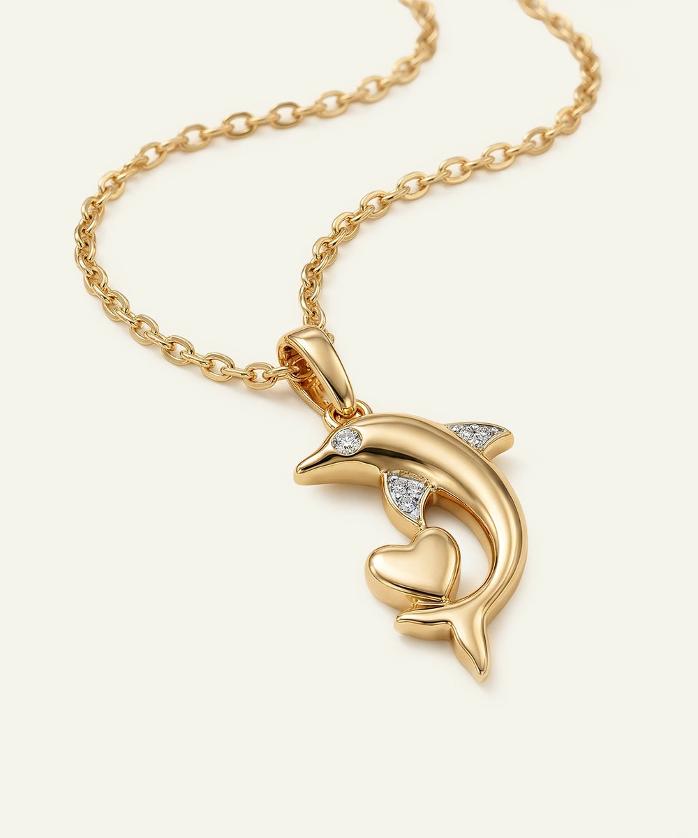 Gold dolphin pendant necklace with heart on a white background