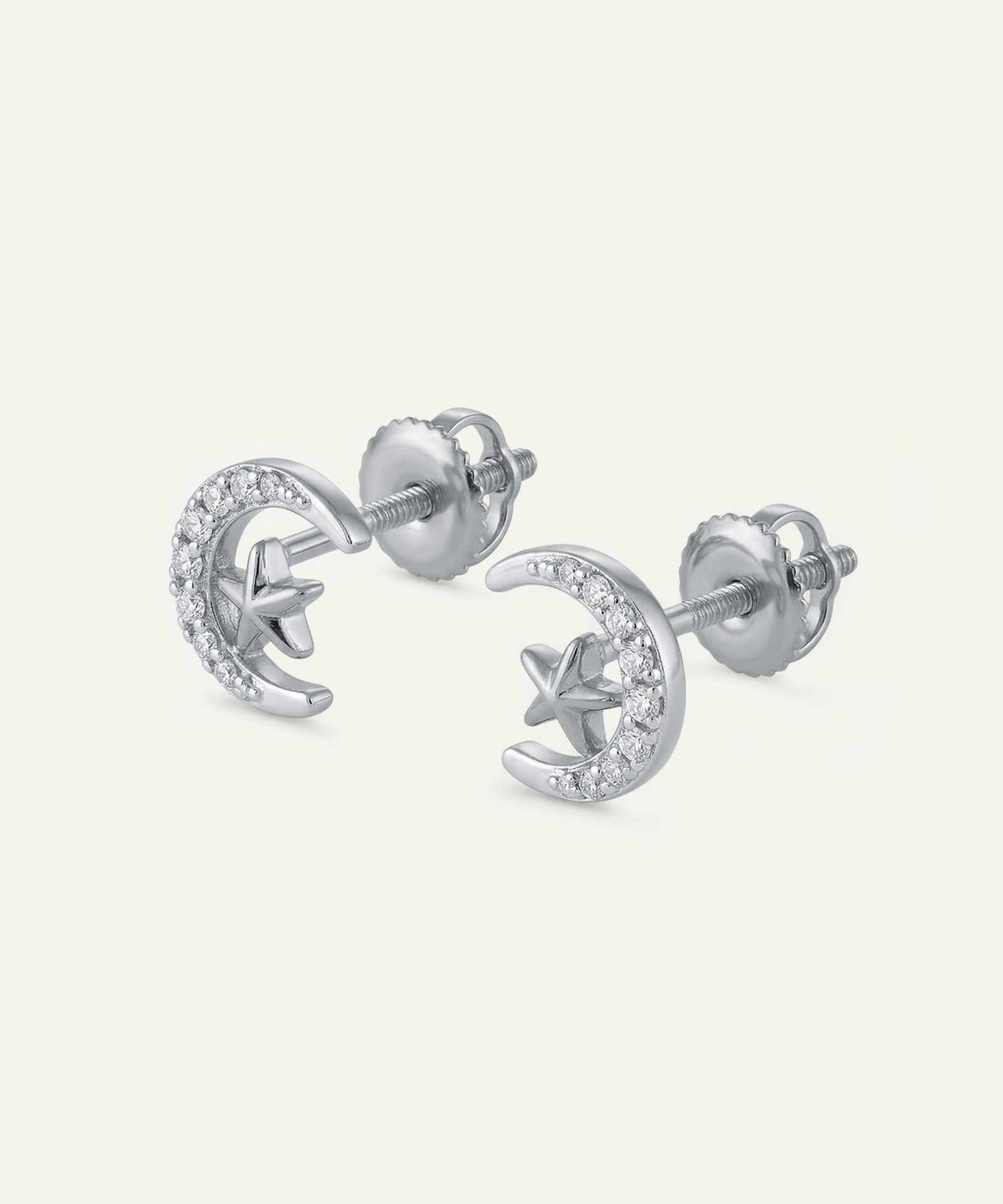 Silver earrings with star and moon designs on a white background