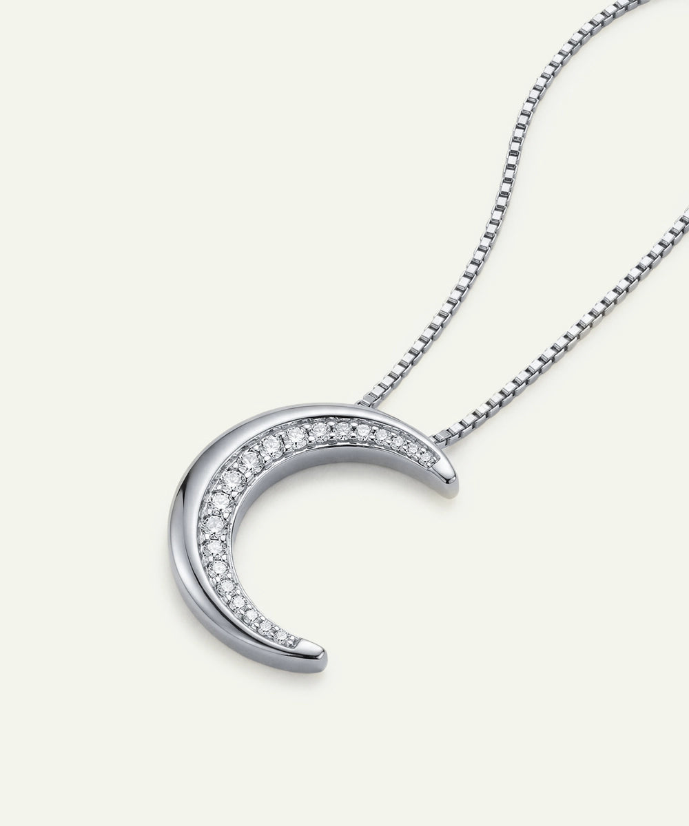 Silver crescent moon necklace with diamonds on a white background