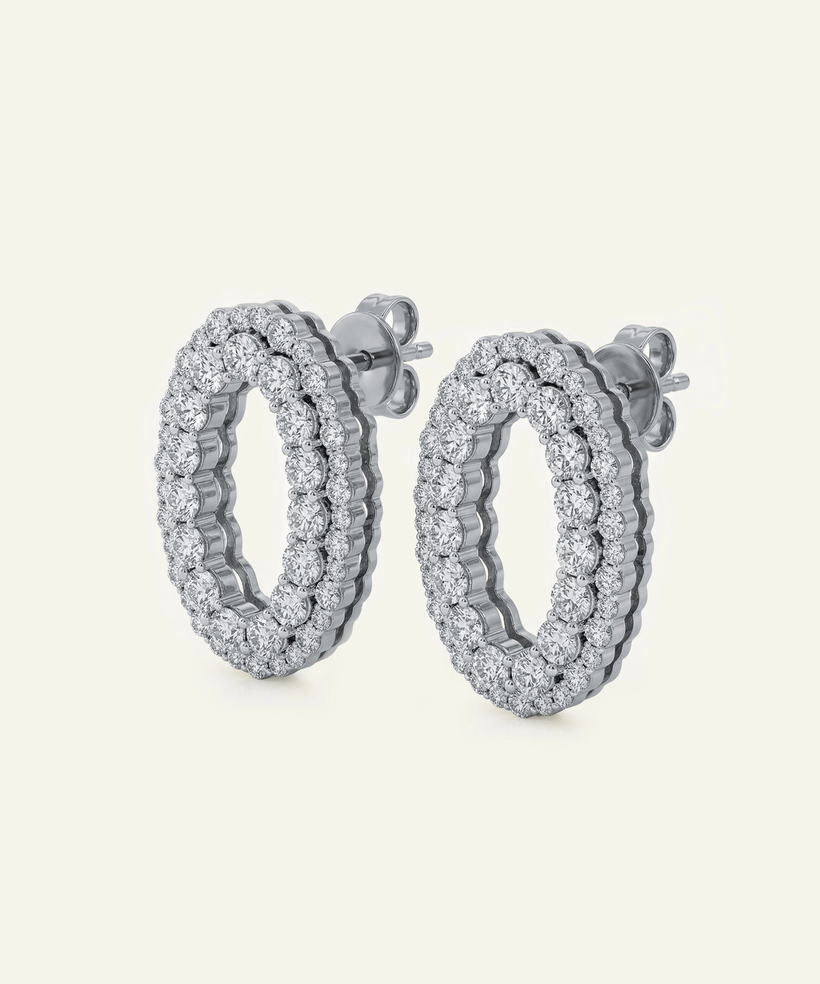 Pair of silver hoop earrings with clear gemstones on a light gray background
