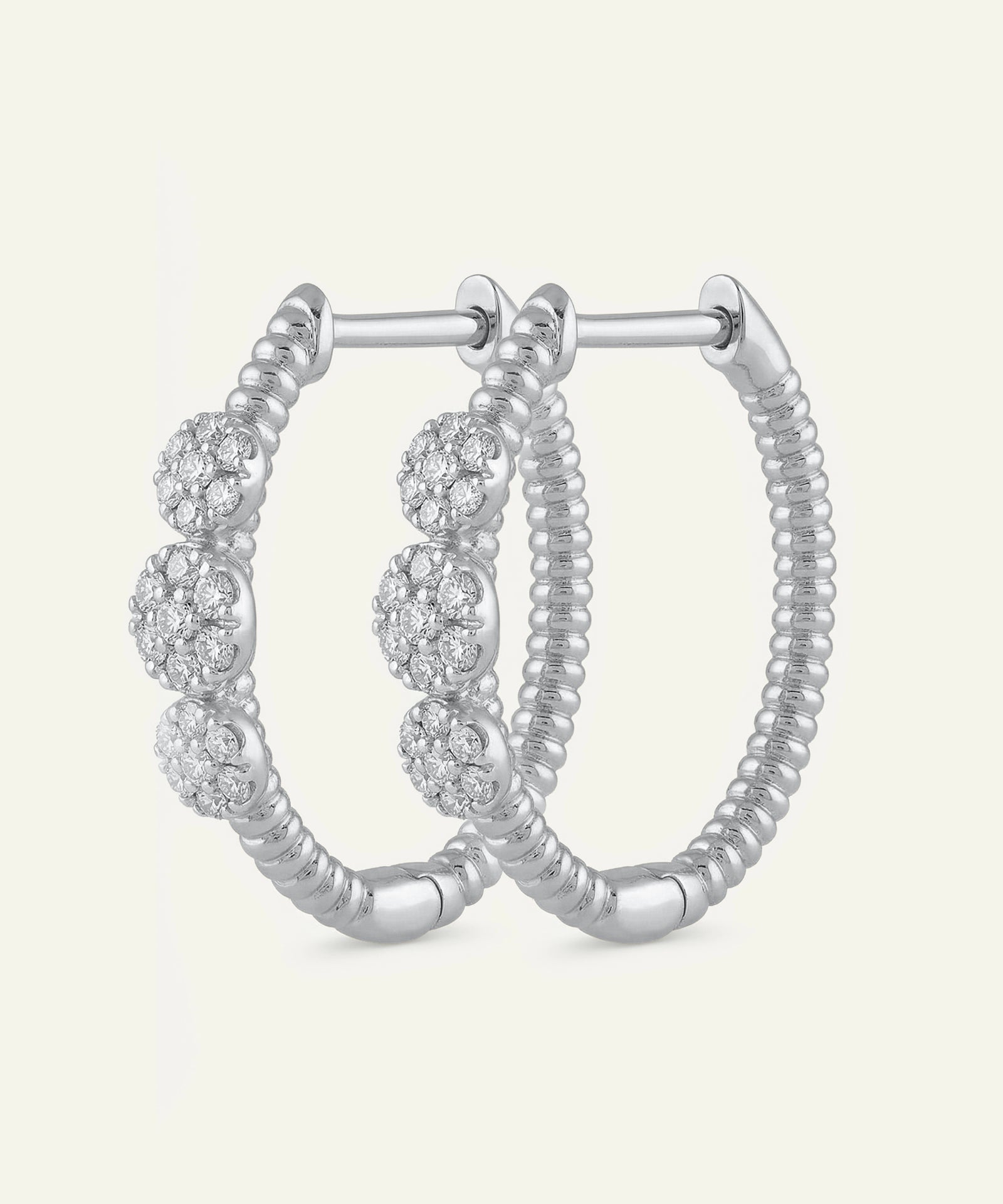 Silver hoop earrings with embedded stones on a light gray background