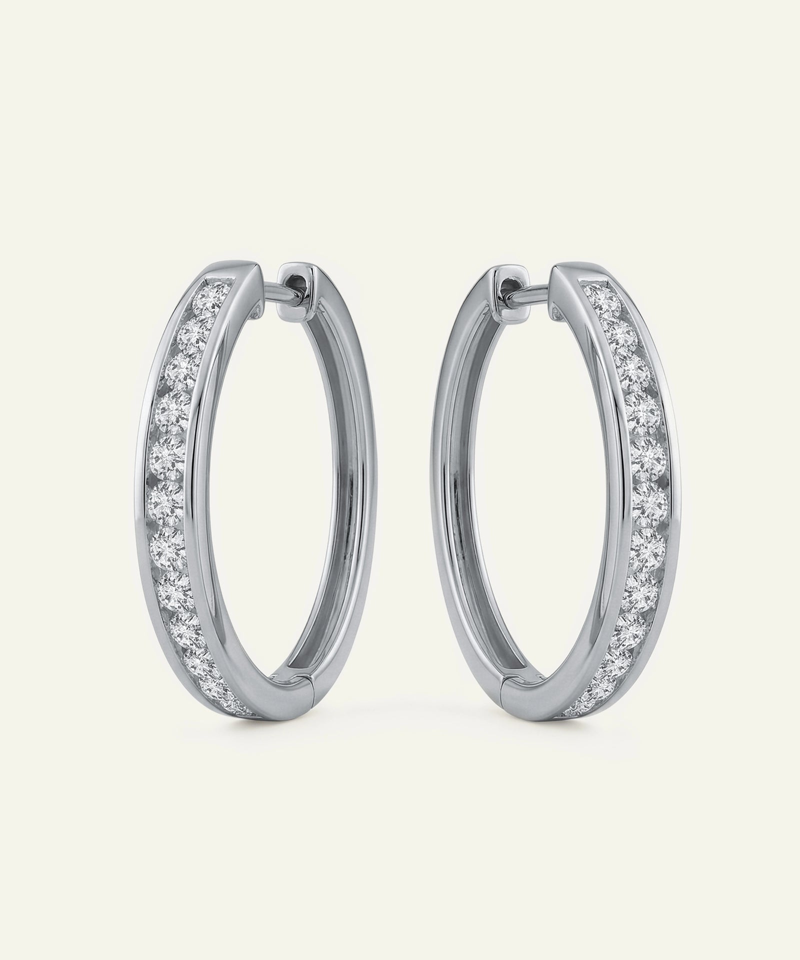 Pair of silver hoop earrings with clear gemstones on a light gray background