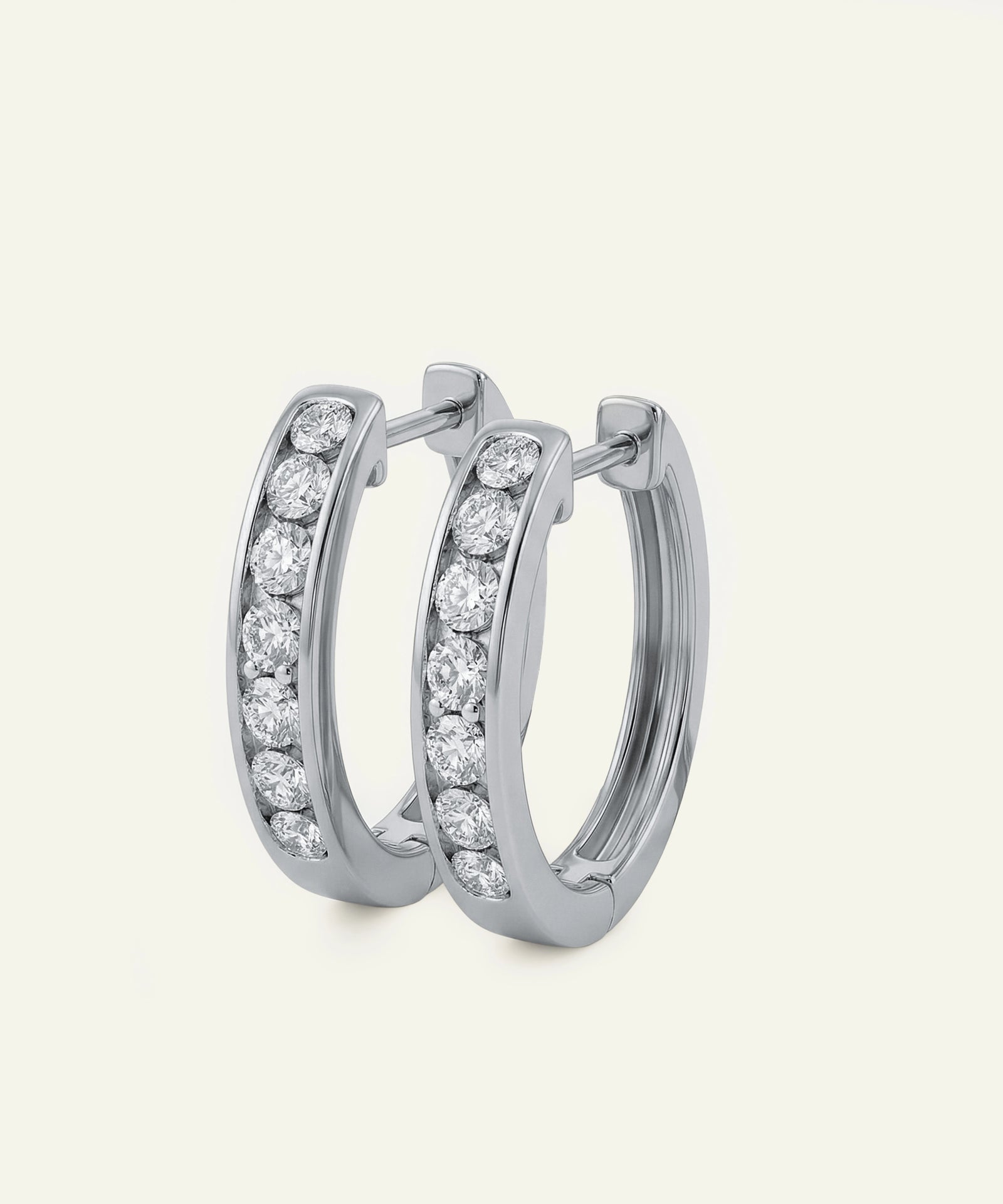 Pair of silver hoop earrings with embedded diamonds on a light gray background
