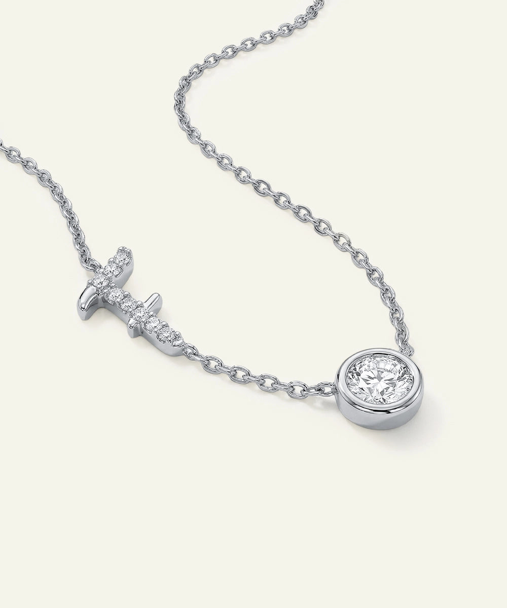 Silver necklace with a cross pendant and round diamond on a white background