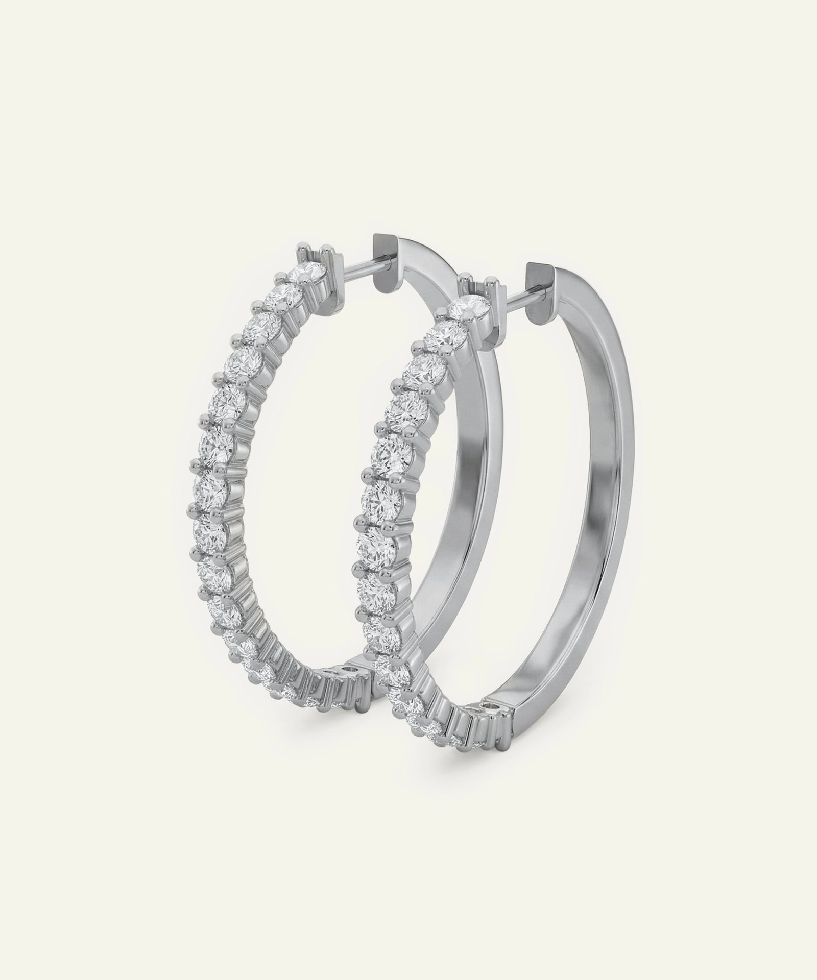 Pair of silver hoop earrings with clear gemstones on a light gray background