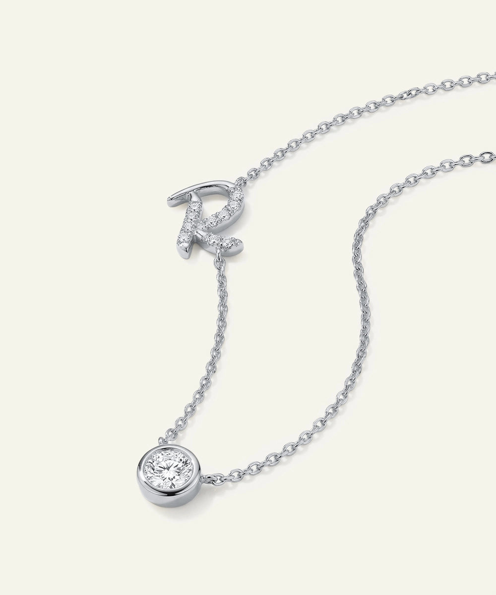 Silver necklace with a round pendant and letter 'R' on a white background