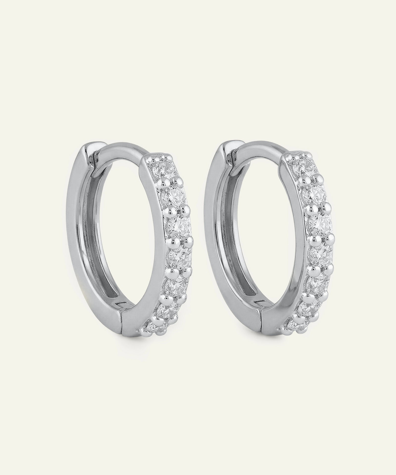 Pair of silver hoop earrings with clear gemstones on a light gray background