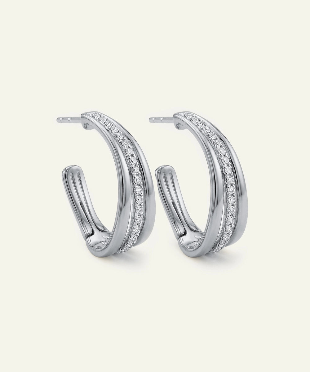 Pair of silver hoop earrings with embedded stones on a light gray background