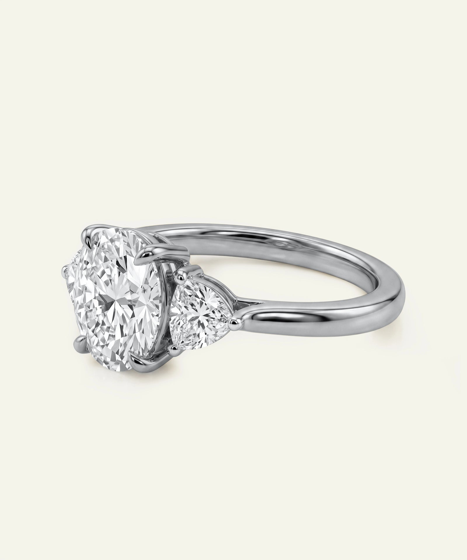 Side view of an oval diamond three-stone ring with a polished white gold band.