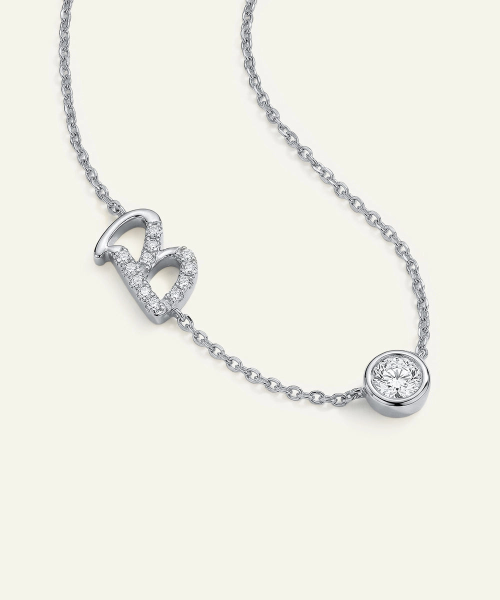 Silver necklace with a heart pendant and round diamond on a white background