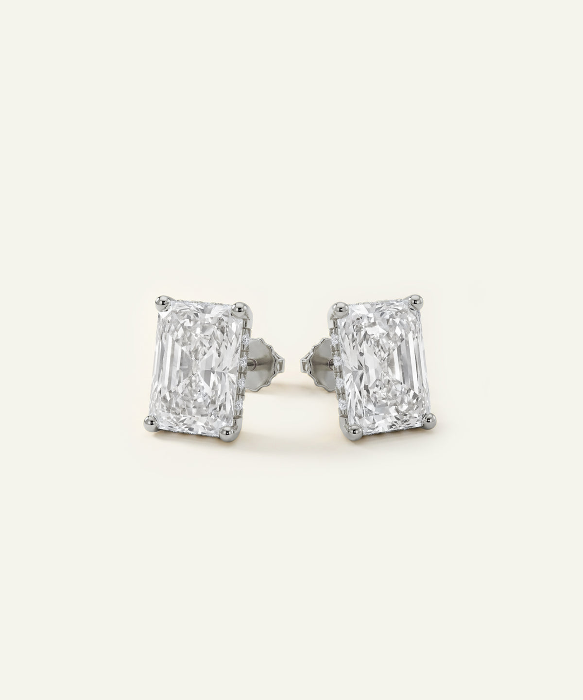A pair of rectangular baguette diamond stud earrings in a silver-toned setting, shown on a plain off-white background.