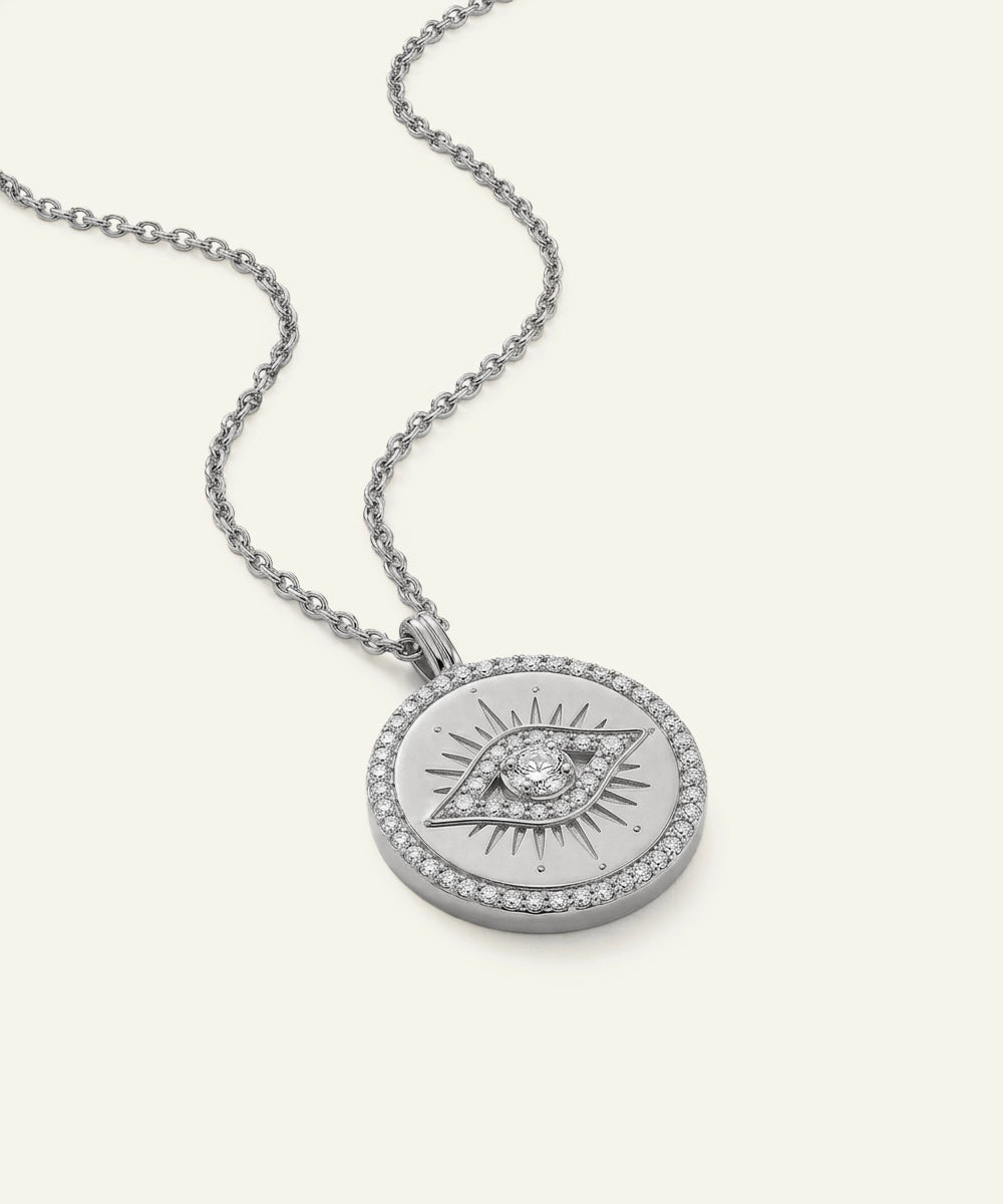 Silver necklace with a round pendant featuring an eye design on a white background