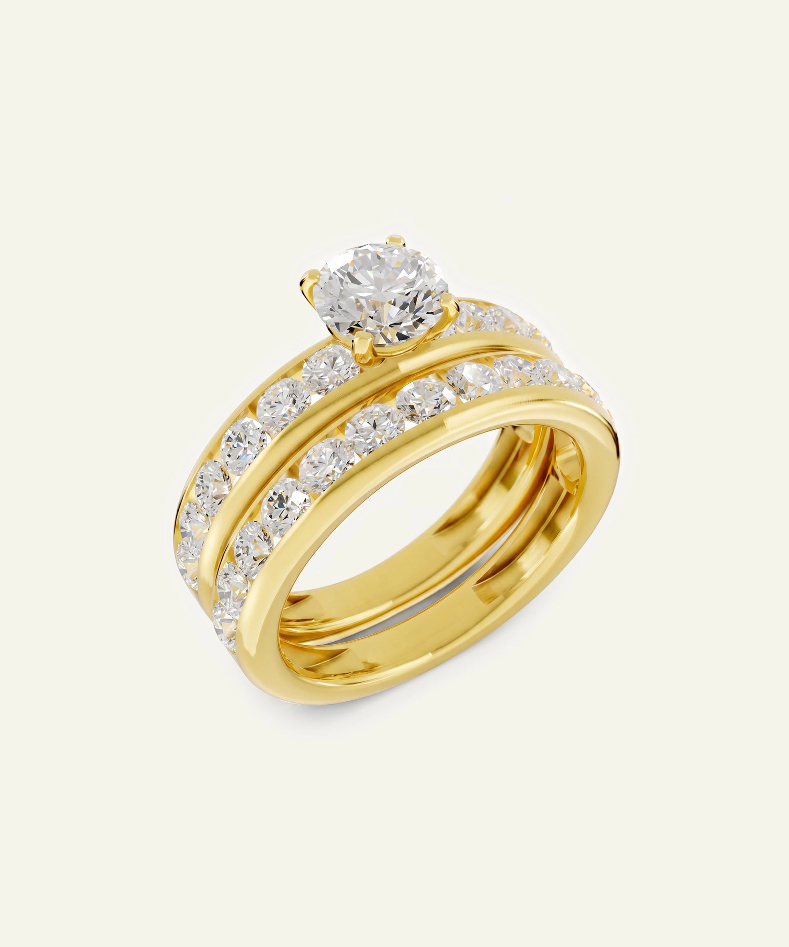 A yellow gold wedding ring set featuring a solitaire engagement ring with a round diamond and a matching band with pavé diamonds, displayed on a light cream background.