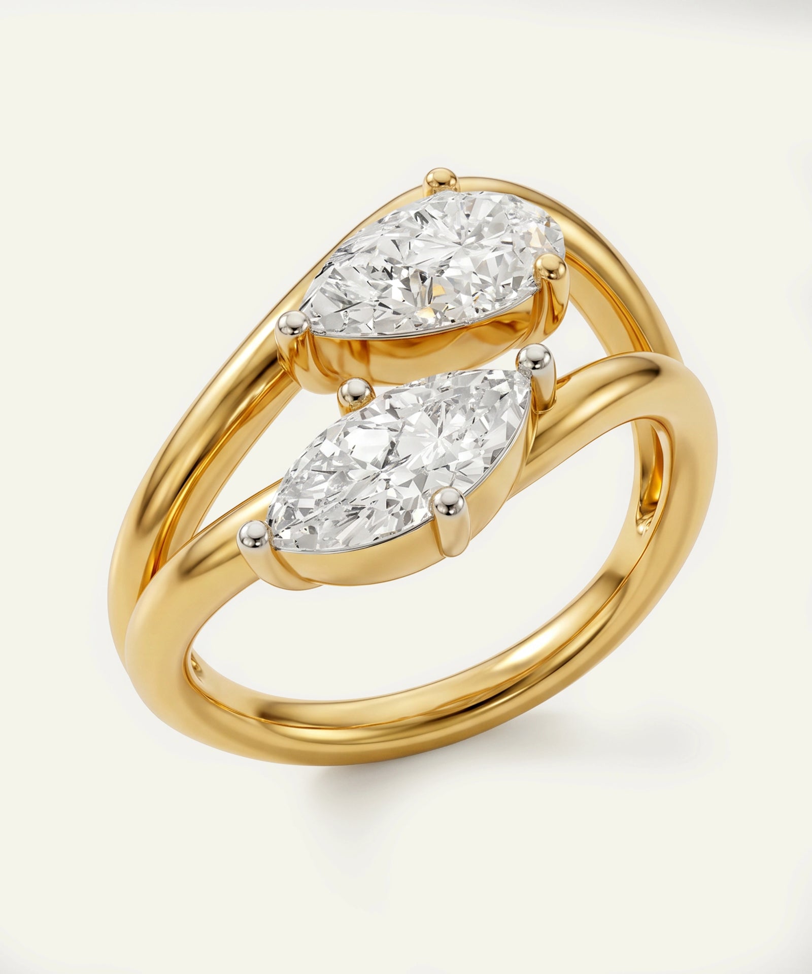 Gold ring with two pear-shaped diamonds on a light background