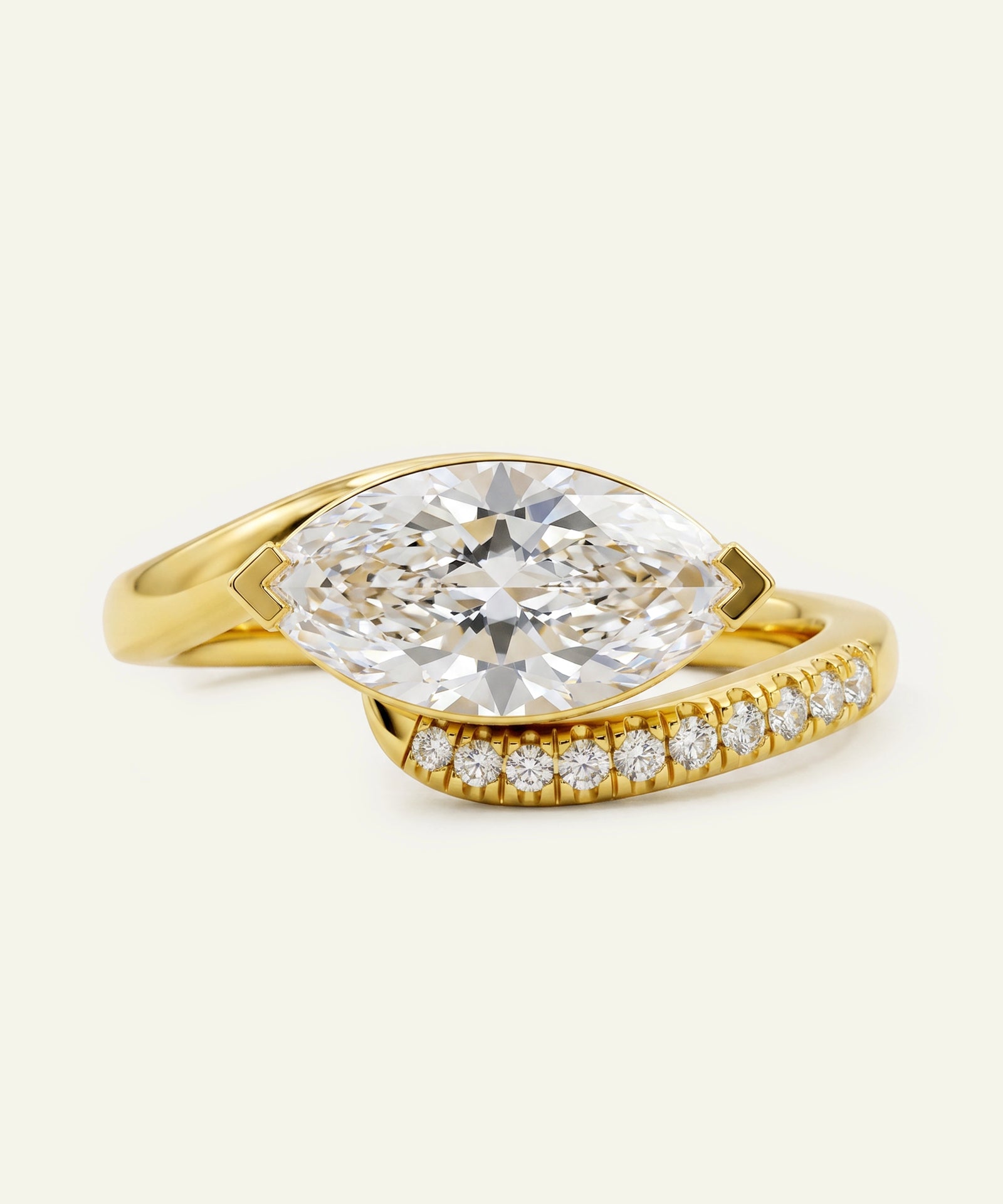 Gold ring with a large diamond and smaller diamonds on the band against a light beige background