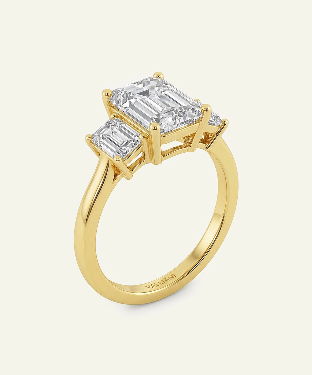 Gold ring with two emerald-cut diamonds on a white background