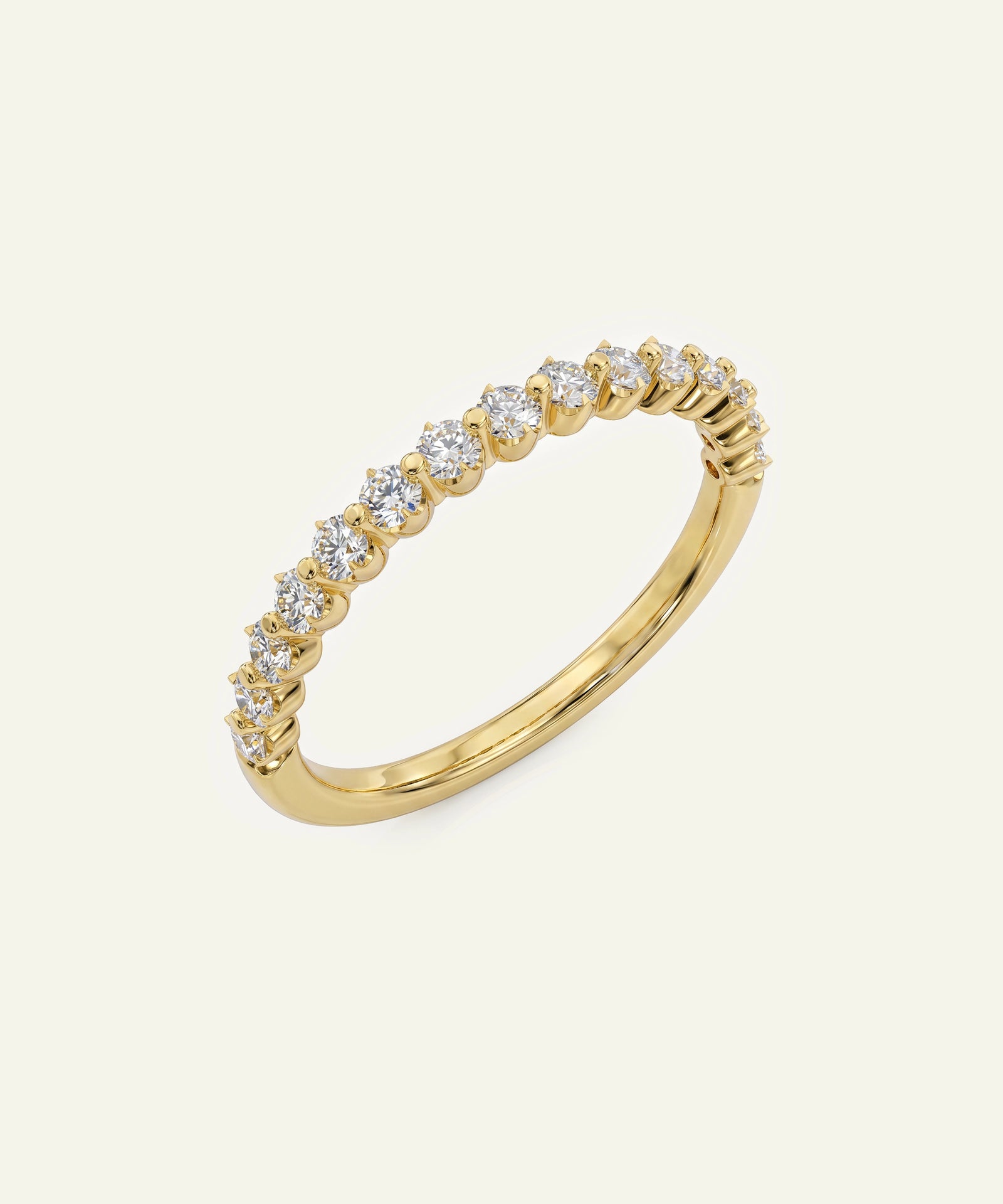 A yellow gold eternity ring featuring a row of round-cut clear gemstones set in a continuous band, shown on a light cream background.