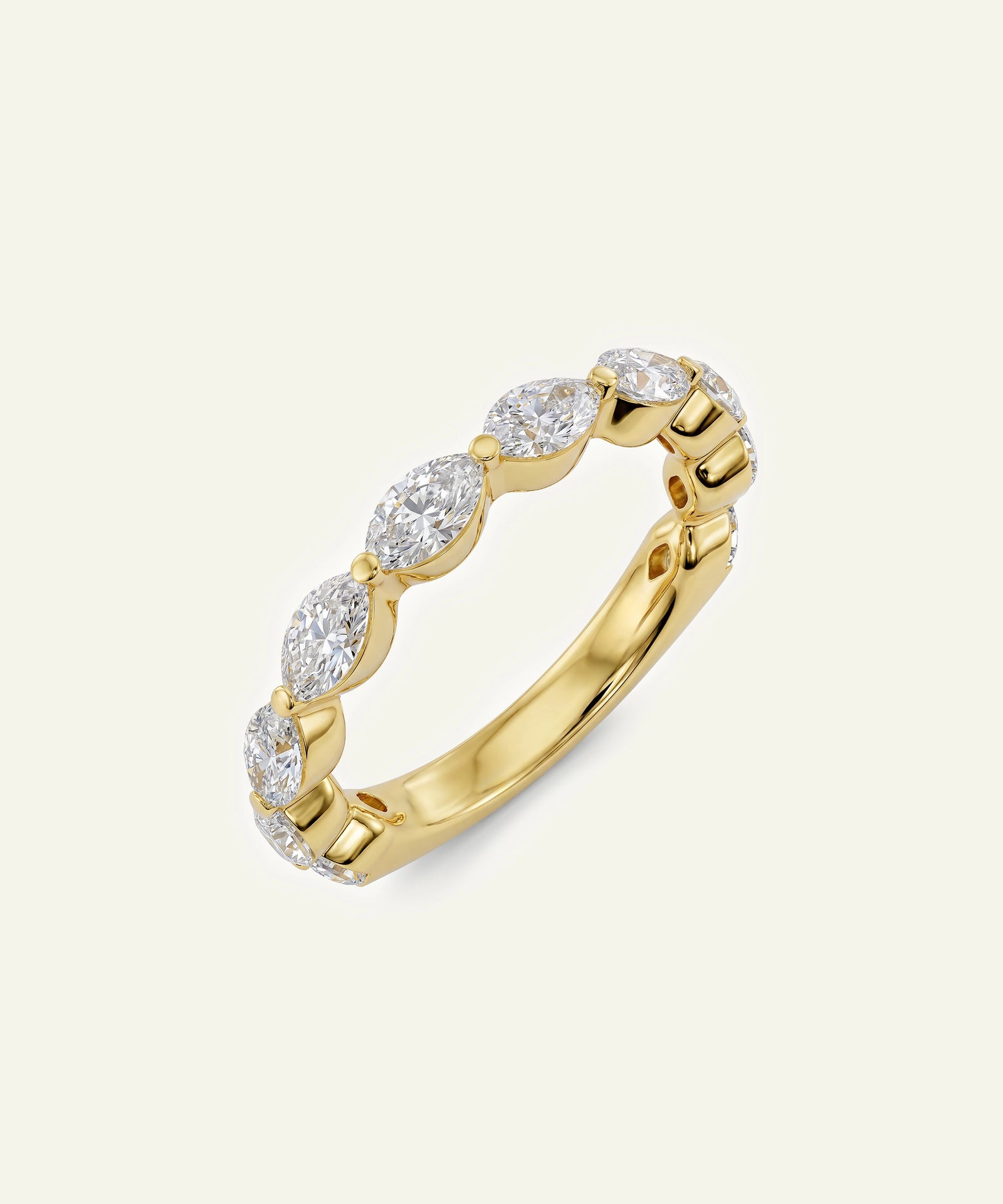 A yellow gold eternity-style ring featuring a row of marquise-cut clear gemstones, photographed on a clean off-white background.