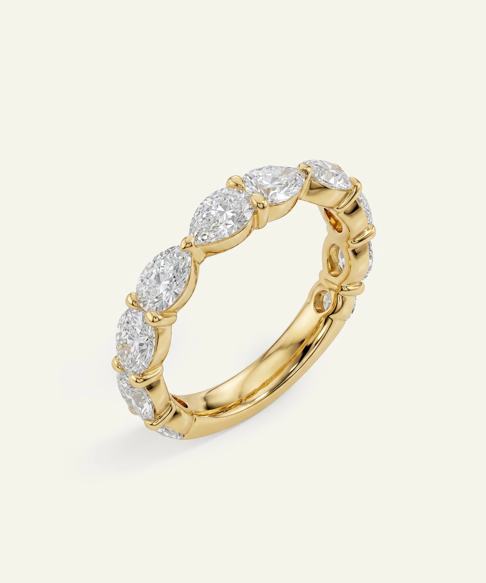 A yellow gold eternity ring featuring a row of marquise-cut clear gemstones, photographed on a clean, light off-white background.