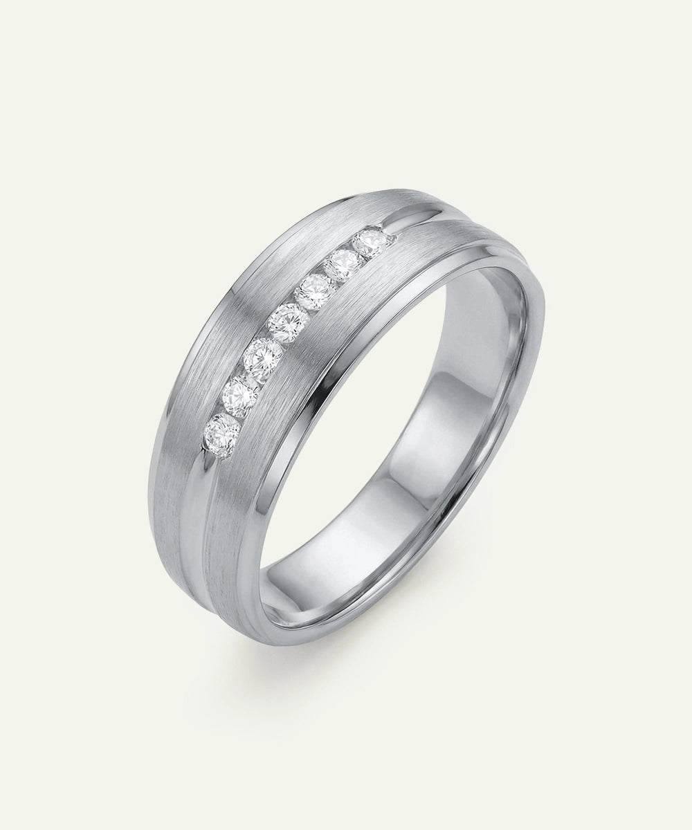Silver ring with embedded diamonds on a light gray background