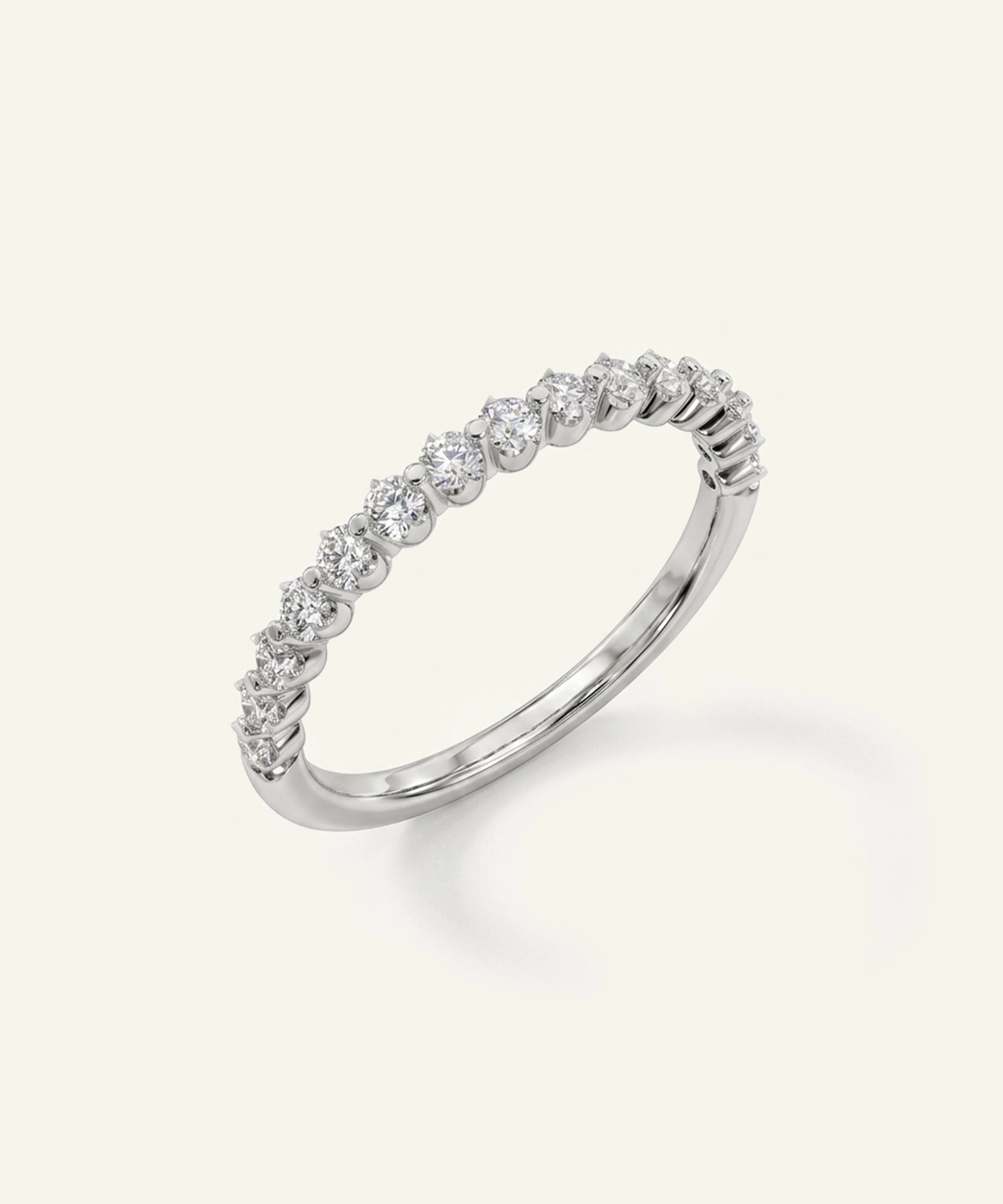A silver-toned diamond band ring with a row of small round-cut diamonds set along the outer edge, shown on a light cream background.
