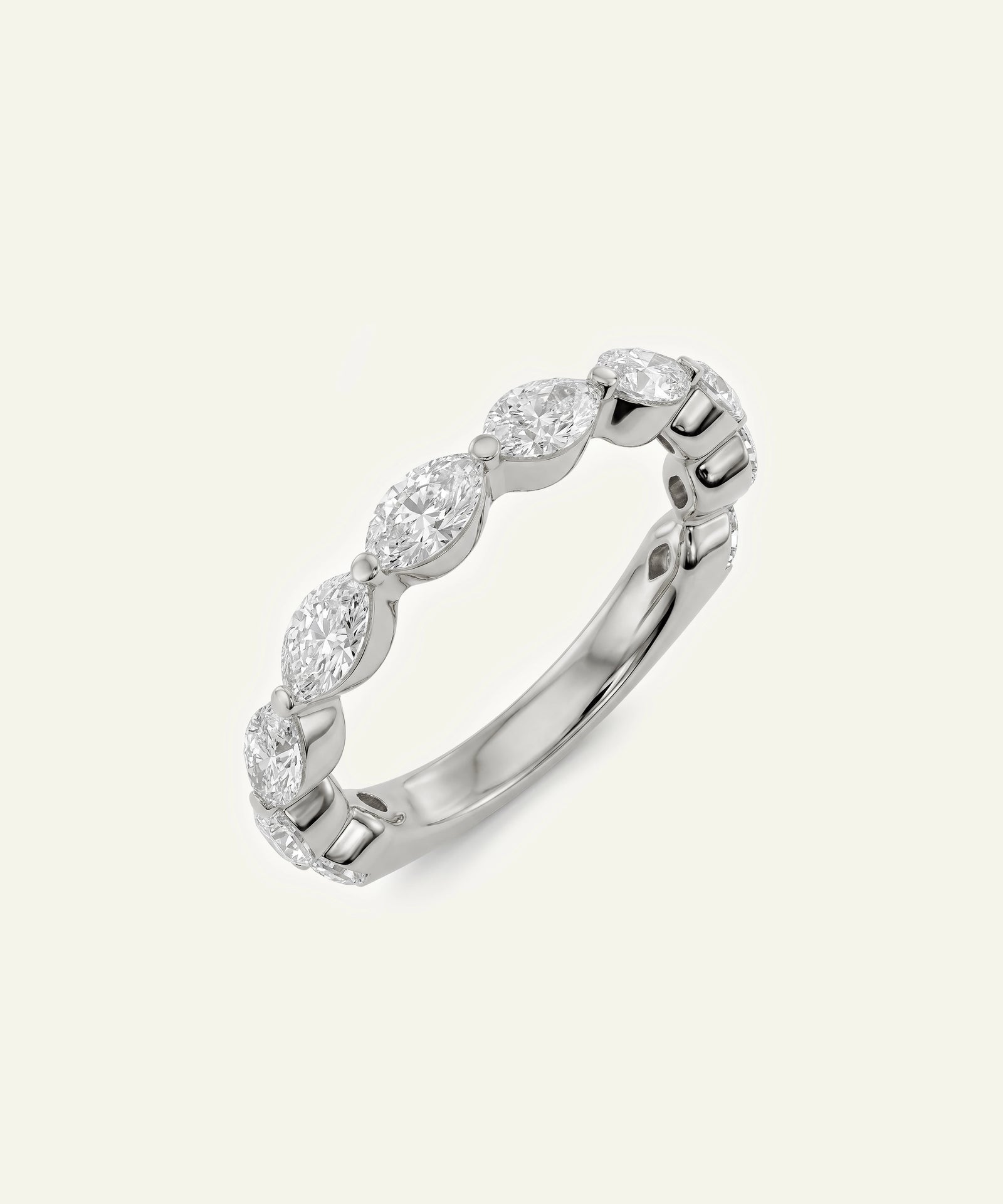 A silver-toned diamond band ring featuring a row of marquise-cut diamonds set in a polished metal band, shown on a light cream background.